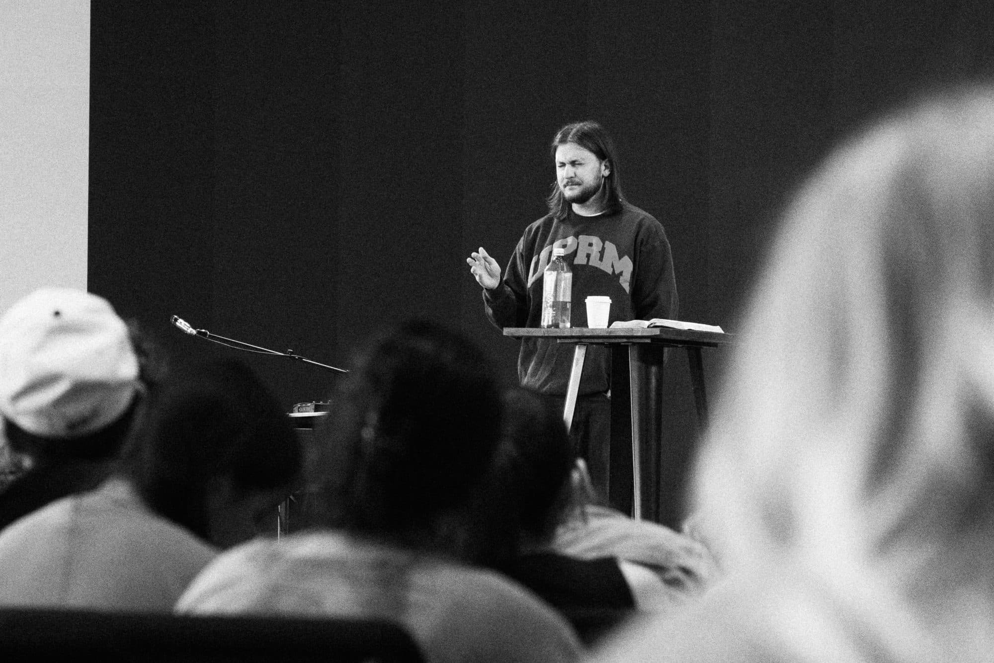 Chase preaching at a podium, seen from behind the people listening
